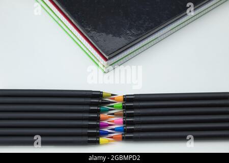 foreground of set of colored self-tips pens and markers and notebooks on white background Stock Photo