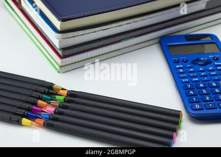 group of school tools with notebooks, markers, pens, calculator ready for back to school on white background Stock Photo