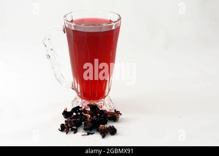 Fresh refrigerated Roselle juice glass with dried Roselle herbs isolated on white background, a dark red-purple colored bissap wonjo juice Stock Photo