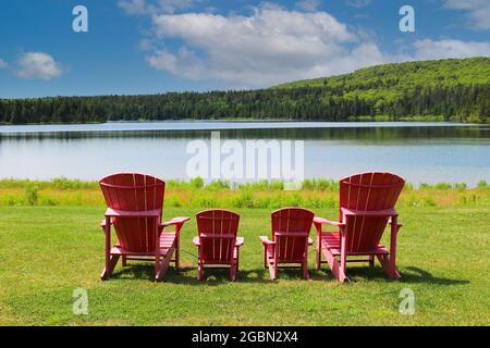 red plastic adirondak chairs in front of the beautiful  view at Wolfe Lake in Fundy National Park in New Brunswick, Canada Stock Photo