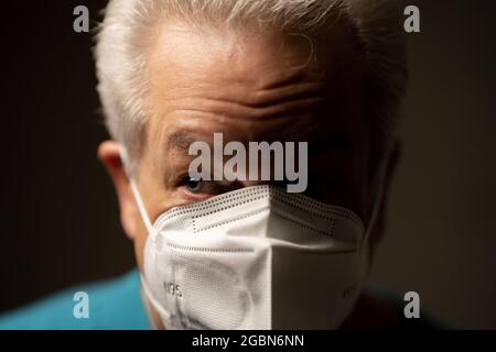 Side light photo of an old man wearing a face mask Stock Photo