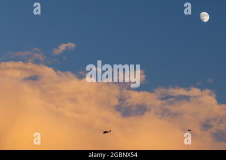 Colorful clouds with the moon, a plane and a helicopter over the Salt Lake Valley at sunset in the summer, Utah Stock Photo
