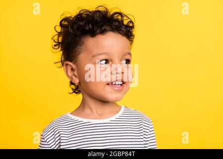 Photo portrait cheerful small boy looking blank space smiling in striped shirt isolated bright yellow color background Stock Photo