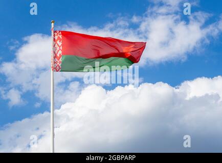 Flag of Belarus on flagpole waving against blue sky Stock Photo