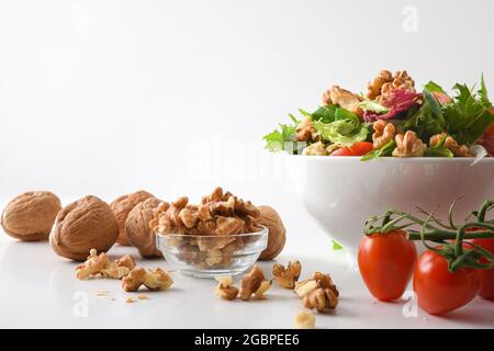 Mediterranean salad with walnuts in a bowl with lettuce tomatoes and onion on a white table isolated background. Front view. Stock Photo