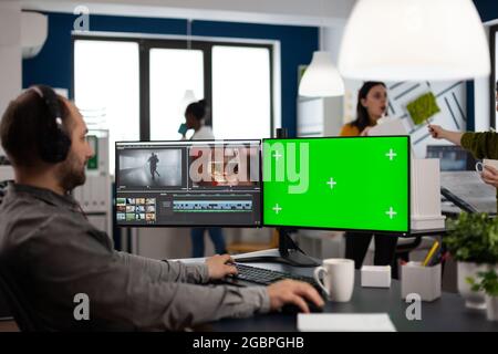 Video maker editor editing movie project using post production software working in post production agency at pc with green screen, chroma key, mock up isolated display. Man processing audio montage Stock Photo