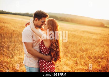 Back view photo of a loving couple embracing and having intimate moments in a field during a perfect sunset Stock Photo
