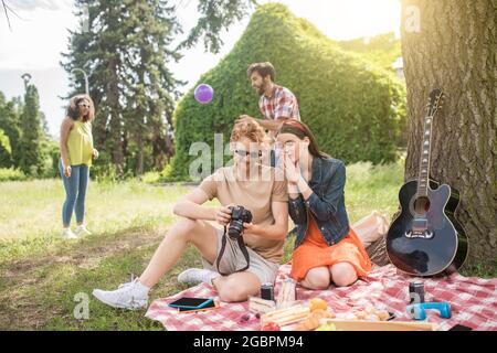 Guy and girlfriend looking photos and friends behind Stock Photo