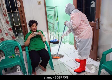 Bogor, Indonesia. 04th Aug, 2021. Nurhasanah mopping the floor of the house.Nurhasanah (37) a member of the volunteer Polisi Masyarakat takes care of a disabled patient suspected to be with Covid-19 under going self isolation. Lapor Covid-19, a civil society coalition that crowdsources coronavirus information throughout the country reported rate of Covid-19 deaths. (Photo by Wisnu Agung Prasetyo/SOPA Imag/Sipa USA) Credit: Sipa USA/Alamy Live News Stock Photo