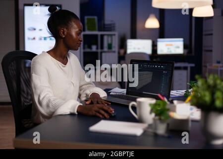Technician engineer analyzing cad software 3D concept of container working in start-up company late at night. African american woman developing industrial prototype using construction technology Stock Photo