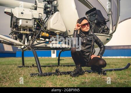 Preteen girl sitting near small helicopter at airfield Stock Photo