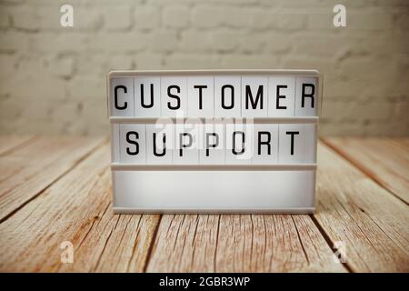 Customer Support word in light box on wooden background Stock Photo