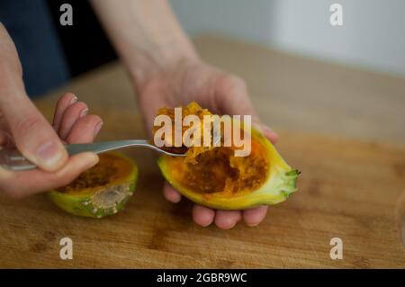 Female eats fresh organic ripe cactus pear or opuntia with a spoon. Exotic fruits, healthy eating concept Stock Photo