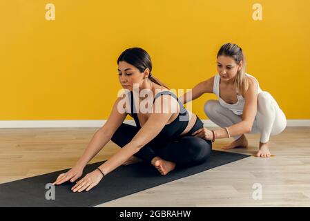 Fitness woman training with her personal trainer at gym. Young couple doing stretching exercises, copy space. Stock Photo