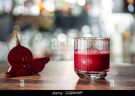 Alcoholic beetroot cocktail beverage in elegant glass on wooden table. Stock Photo