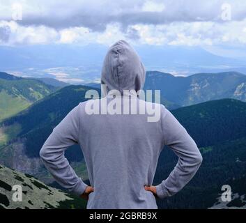 Hiker in grey hoodie looking over mountain panorama from Chopok in the Low Tatras, Slovakia Stock Photo