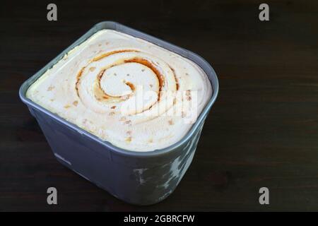 Tub of Tasty and Creamy Salted Caramel Macadamia Nut Ice Cream Isolated on Black Background Stock Photo