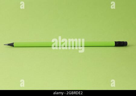 Sharp simple pencil lying on green background closeup Stock Photo