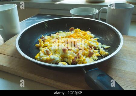 Fresh scrambled eggs with bacon in a pan Stock Photo