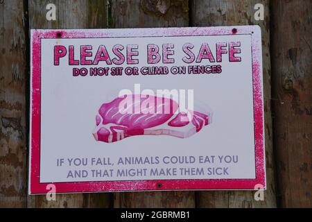 POZNAN, POLAND - Jul 19, 2021: A warning sign saying 'PLEASE BE SAFE DO NOT SIT OR CLIMB ON FENCES' hanging on a wall at the zoo Stock Photo