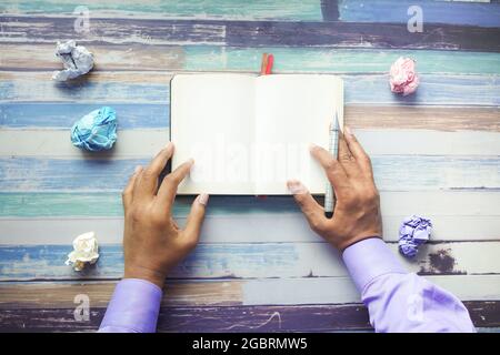 crumpled paper ball and notepad on wooden table. Stock Photo