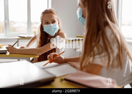School kids holding pencils and using notebooks in classroom Stock Photo