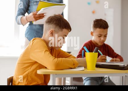Two schoolchildren during a lesson and a test at school Stock Photo