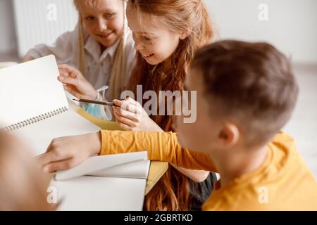 Happy children sitting at the table and using notebooks Stock Photo