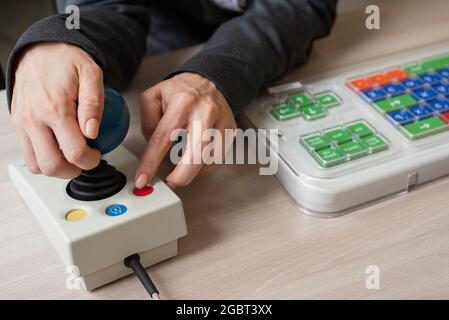 An unrecognizable woman with cerebral palsy is typing on the keyboard. A girl with disabilities works on a specially equipped computer Stock Photo