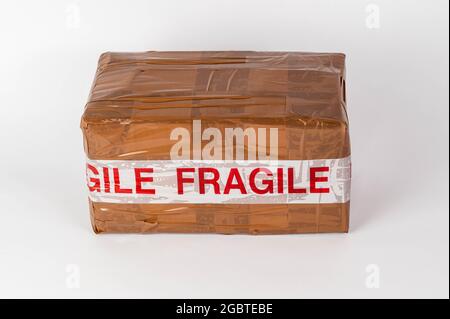 Parcel wrapped up with brown parcel tape and fragile written on in red and white tape Stock Photo