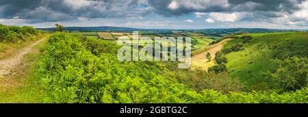 On a summers day in early August, the clouds part and the sun lights up 'The Punchbowl' and Winsford Hill, looking towards Dunkery Beacon which is the Stock Photo