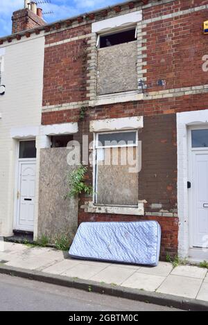 Abandoned town terraced house in central Middlesbrough. It has even got vegetation sprouting from the brickwork, branches of a buddleia Stock Photo
