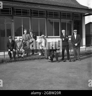 1960s, historical, men in formal suits playing lawn bowls, with other males watching on, infront of the clubhouse at the bowling club at Kelty, Fife, Scotland, UK. In this era, men would wear suits for almost all their activities, at work, on the beach and as seen here, to playing sport and and a leisurely game of bowls. Stock Photo