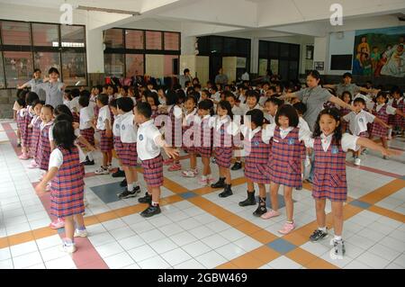 A group of kindergarten students line up in a hall with their teachers. Stock Photo