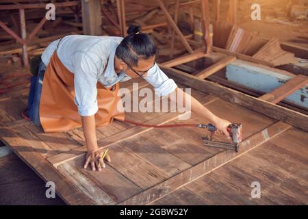 Closeup of a man carpenter using a nail gun.Carpenter using air nail gun doing wooden furniture work,vintage style Stock Photo