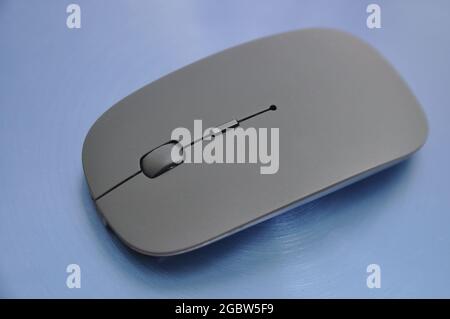 Wireless rechargeable computer mouse on a blue background. Technology Stock Photo