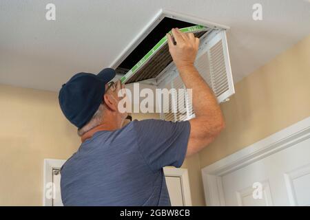 Senior man chaning overhead air conditioning filter Stock Photo