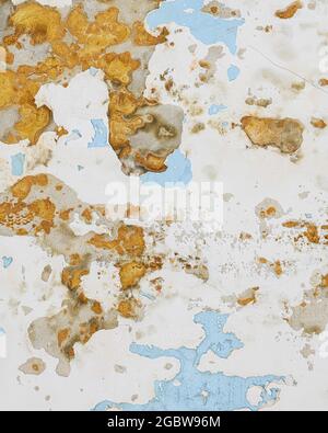 Peeling blue and brown paint on concrete wall forms abstract background Stock Photo
