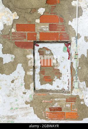 Decayed red brick wall with peeling paint forms abstract background Stock Photo