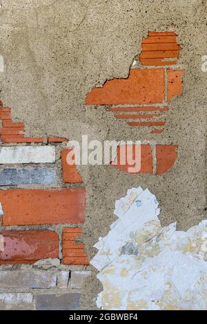 Decayed red brick wall with peeling paint forms abstract background Stock Photo