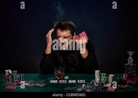 Bearded casino player man playing poker on green table Stock Photo