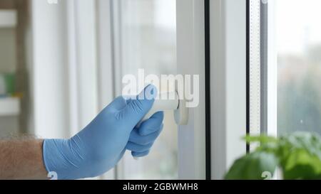 Hand with Protective Glove Opens a Window in a Hospital Room Stock Photo