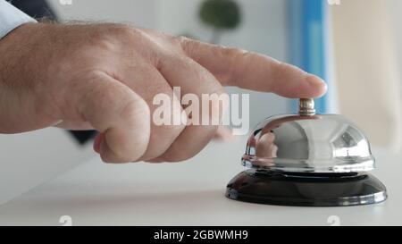 Tourist in Hotel Reception Presses the Bell Button Calling the Receptionist Stock Photo