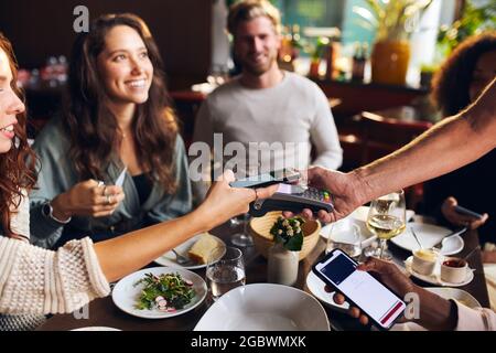 Friends paying contactlessly in restaurant Stock Photo