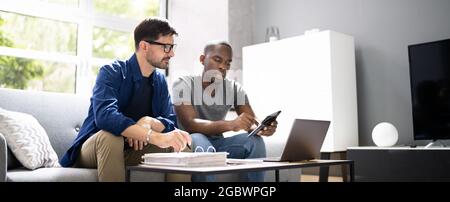 Happy Gay Couple Doing Taxes And Income Planning With Calculator Stock Photo