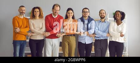 Group of happy smiling diverse people standing in row all together and holding hands Stock Photo