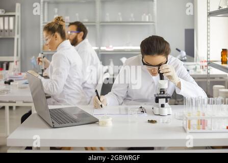 Woman scientist looking through microscope making analysis in laboratory Stock Photo