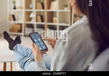 Woman controls the system of her modern Smart House using an app on her smartphone Stock Photo