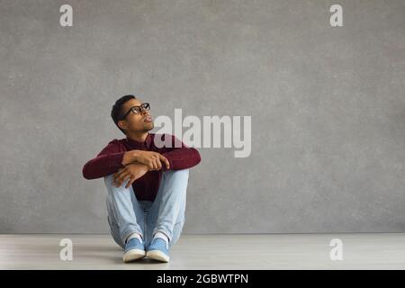 Handsome young African American man is sitting on the floor with a pensive expression on his face. Stock Photo