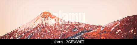 Volcano mountain peak landscape at sunset covered in snow winter background header. Panoramic of Teide Pico del Teide top, Tenerife, Canary Islands Stock Photo